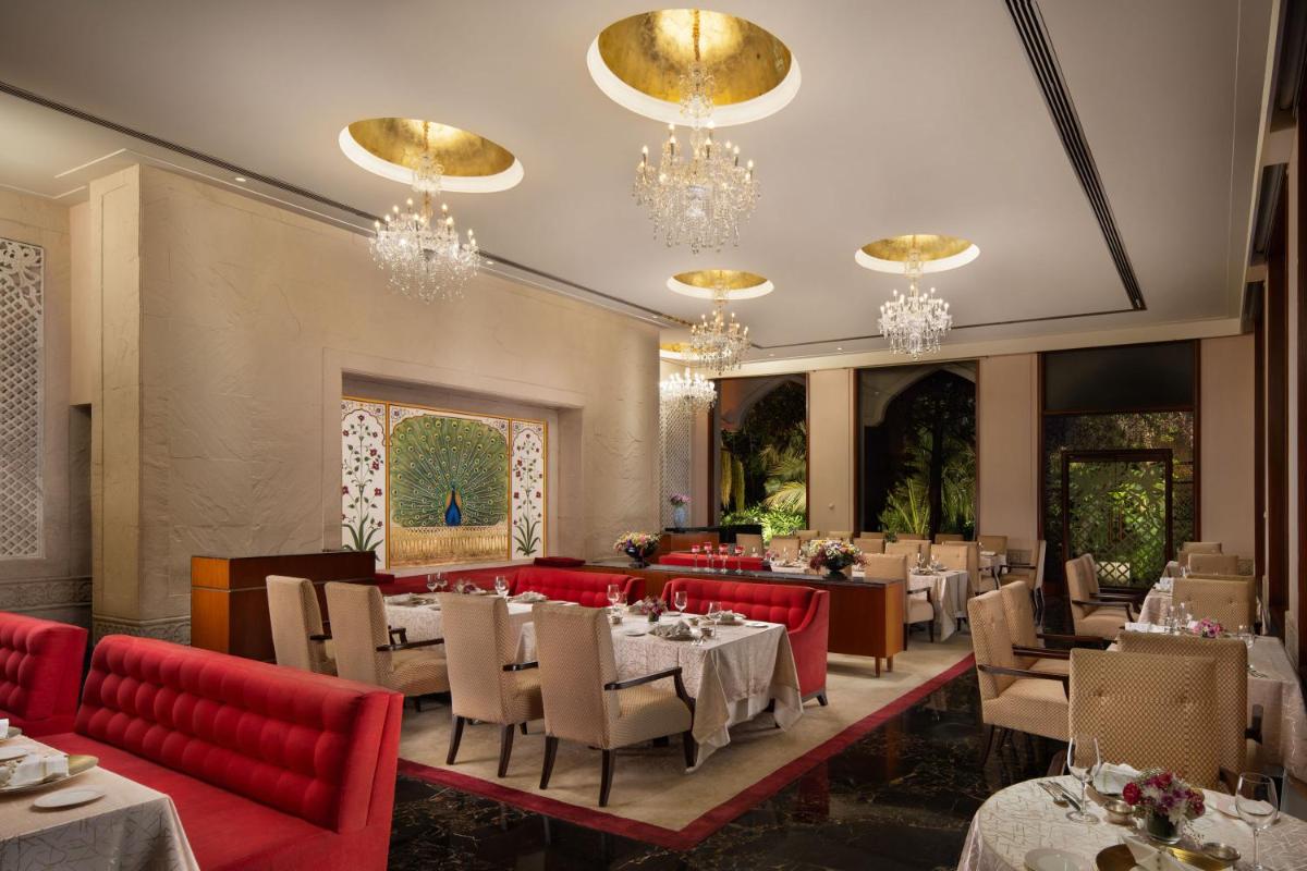 a dining room with tables and chairs and chandeliers at Taj Krishna in Hyderabad