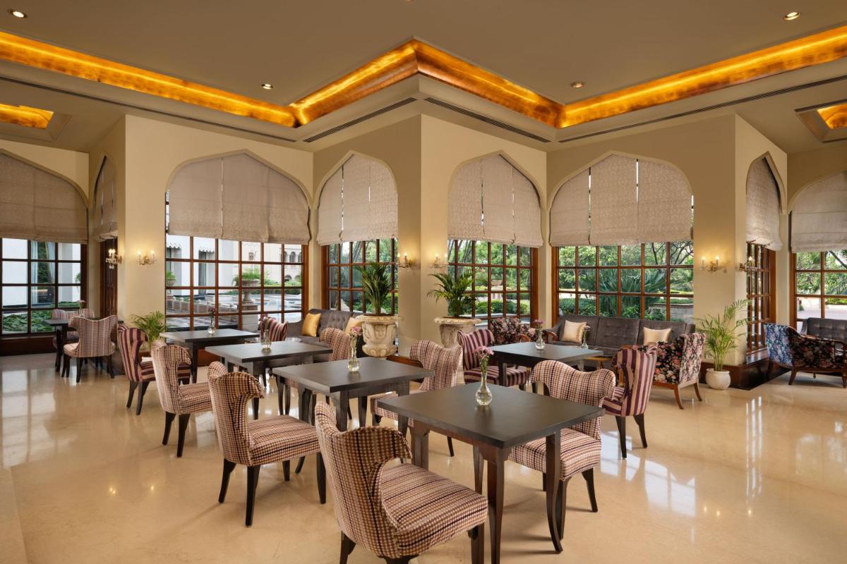 a restaurant with tables and chairs and windows at Taj Krishna in Hyderabad