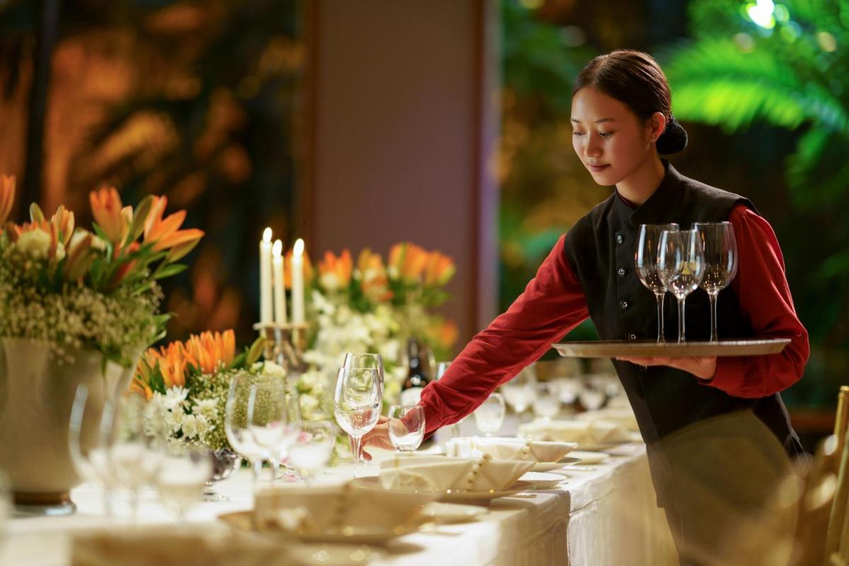 a woman holding a tray of wine glasses on a table at Taj Krishna in Hyderabad