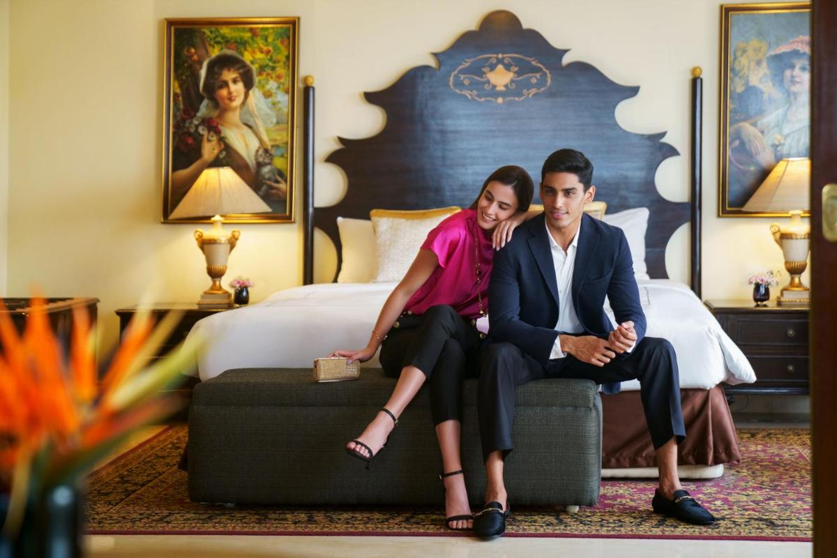 a man and woman sitting on a ottoman in a hotel room at Taj Krishna in Hyderabad
