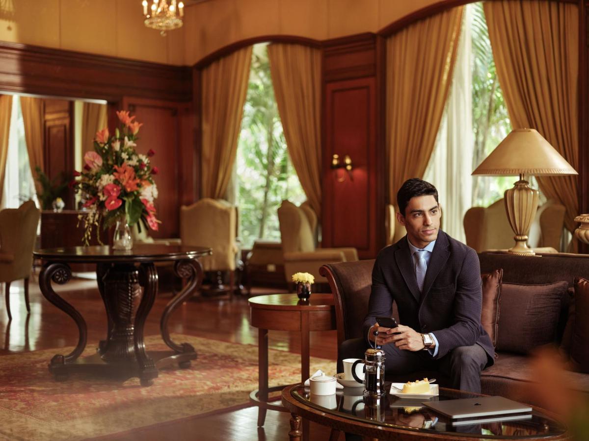 a man in a suit sitting on a couch in a living room at Taj Krishna in Hyderabad