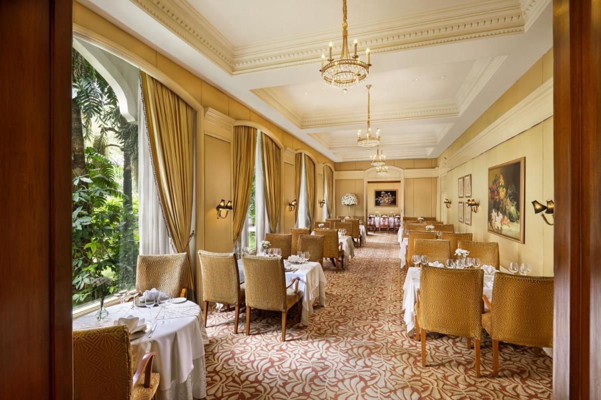 a restaurant with tables and chairs and a chandelier at Taj Krishna in Hyderabad