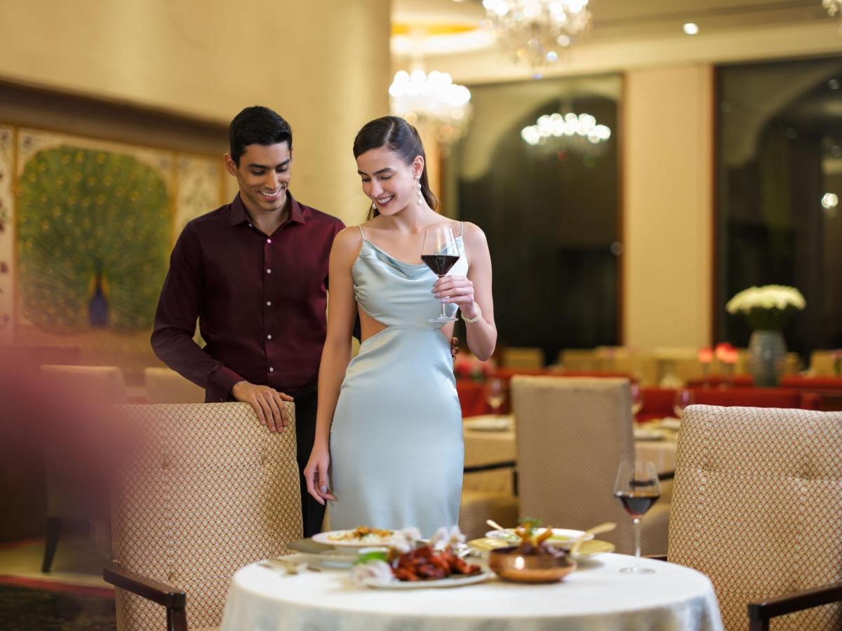 a man and a woman standing next to a table with a glass of wine at Taj Krishna in Hyderabad