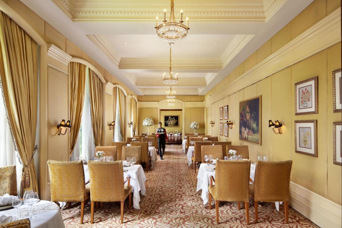 a dining room with tables and chairs and a person in the background at Taj Krishna in Hyderabad