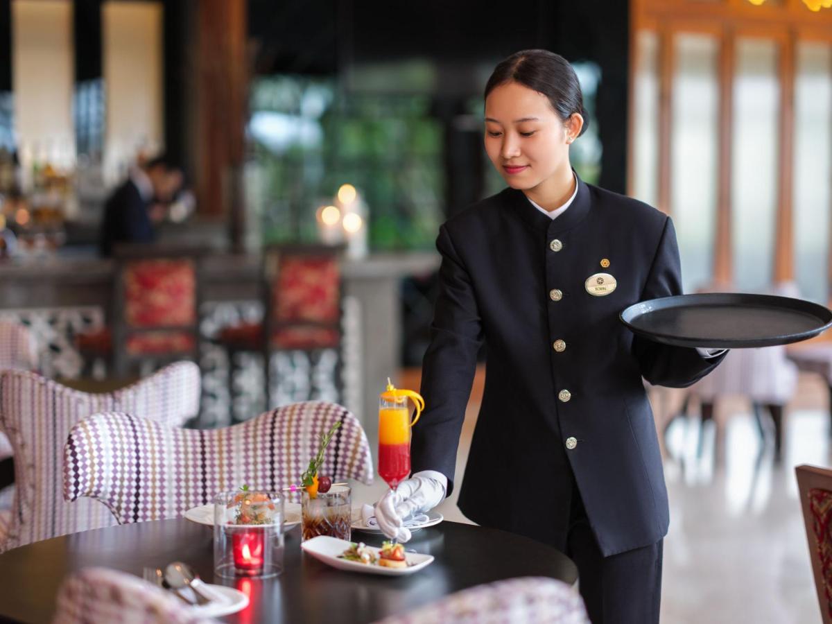 a waitress holding a tray in a restaurant at Taj Krishna in Hyderabad