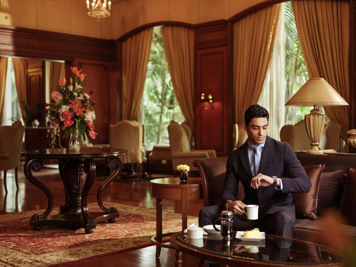 a man in a suit sitting on a couch in a living room at Taj Krishna in Hyderabad
