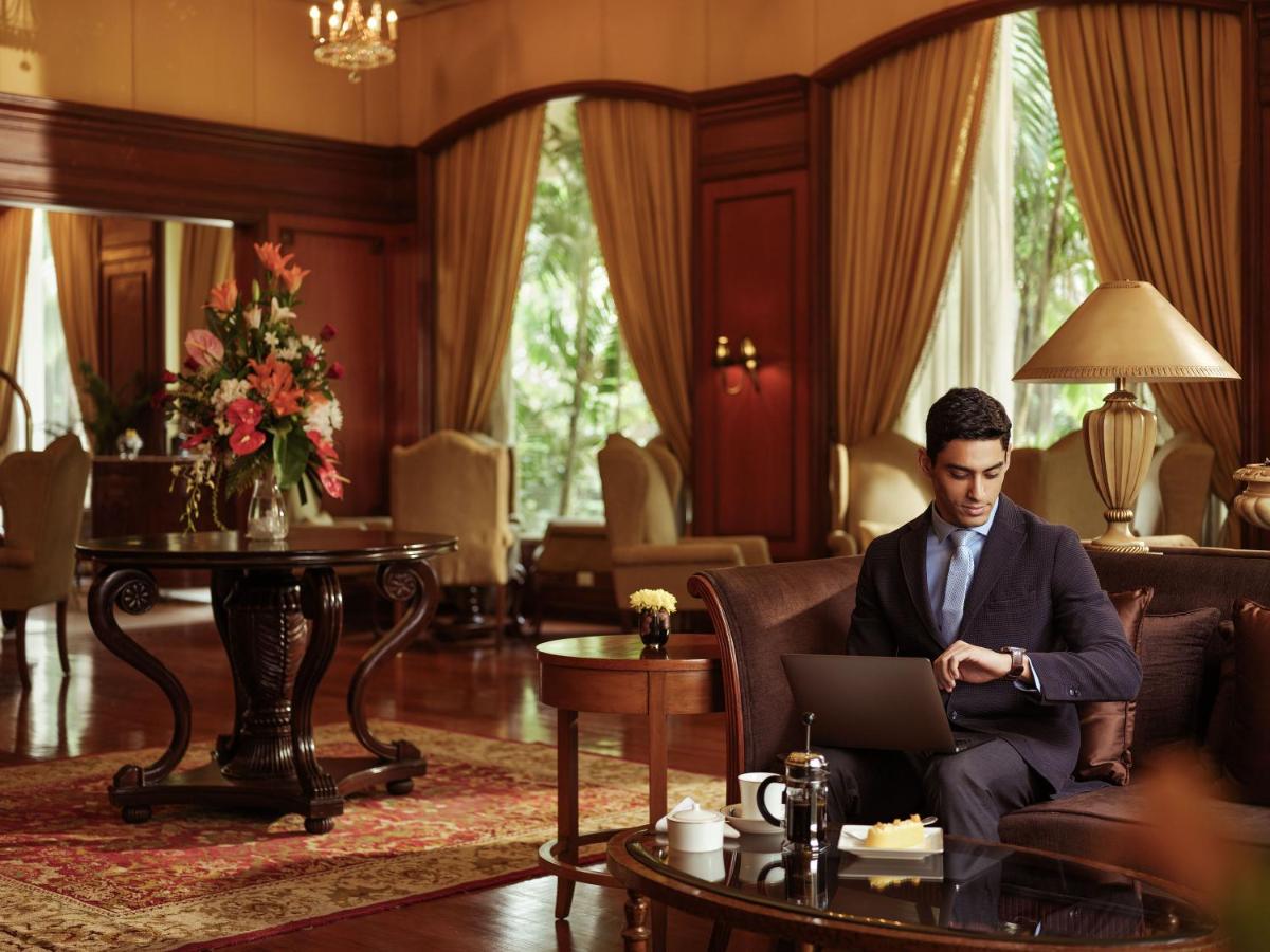 a man in a suit sitting on a couch with a laptop at Taj Krishna in Hyderabad