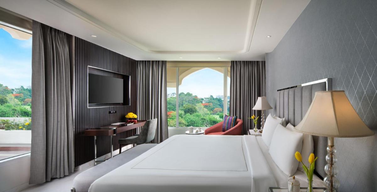 a bedroom with a bed and a desk and a television at Taj Krishna in Hyderabad