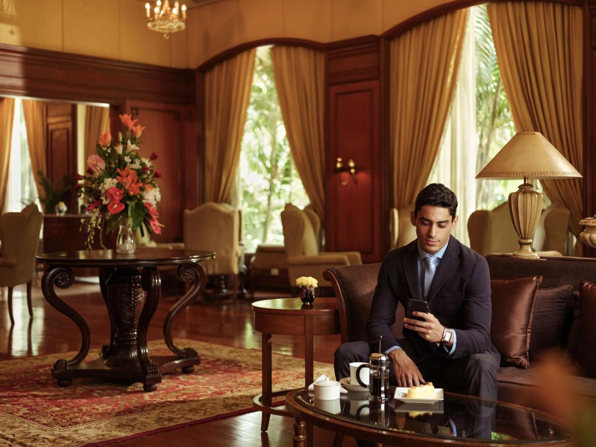 a man sitting on a couch looking at his cell phone at Taj Krishna in Hyderabad