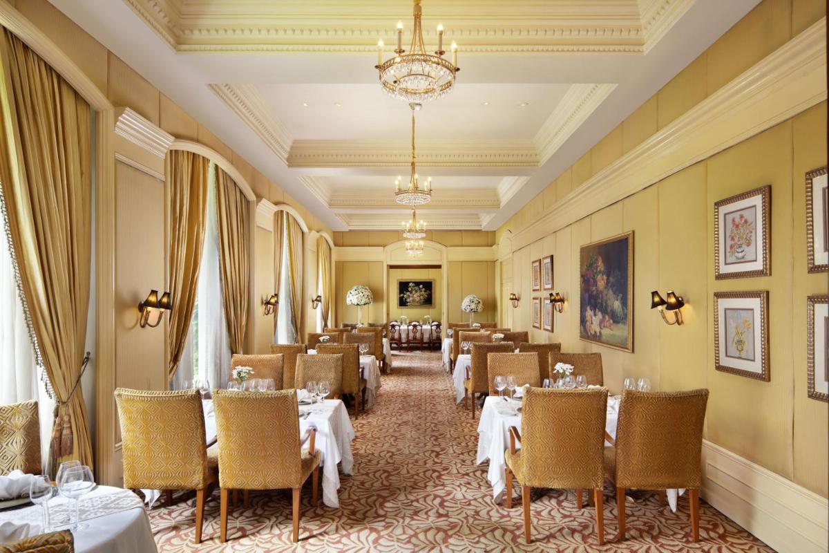 a dining room with tables and chairs and a chandelier at Taj Krishna in Hyderabad