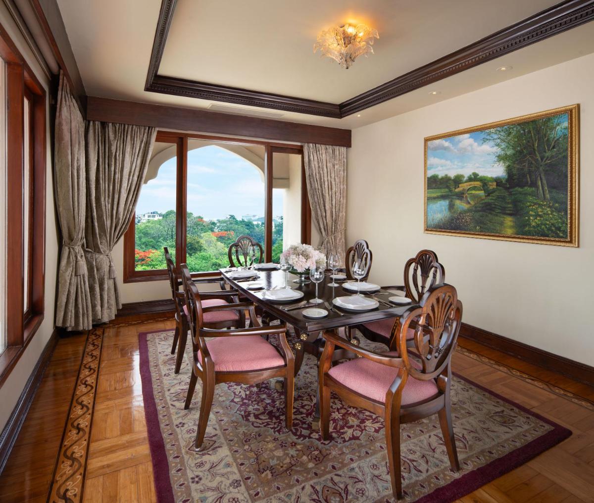 a dining room with a table and chairs and a large window at Taj Krishna in Hyderabad