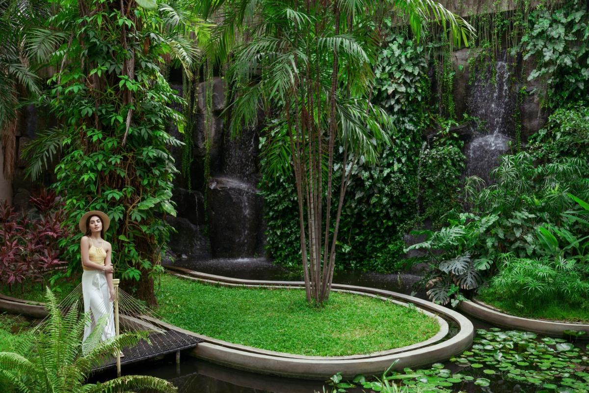 a woman standing in a garden with a waterfall at Taj Krishna in Hyderabad