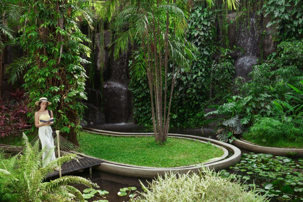 a woman standing in a garden with a waterfall at Taj Krishna in Hyderabad