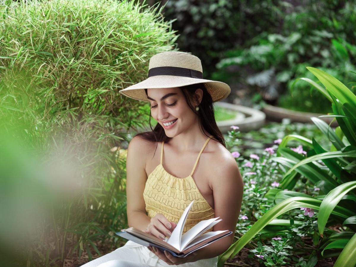 a woman in a hat reading a book at Taj Krishna in Hyderabad