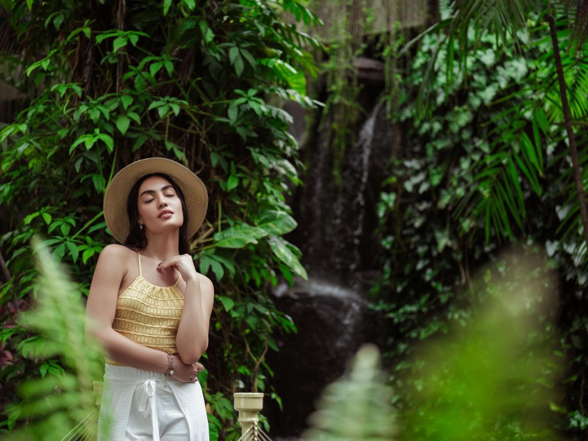 a woman wearing a hat standing in front of a waterfall at Taj Krishna in Hyderabad