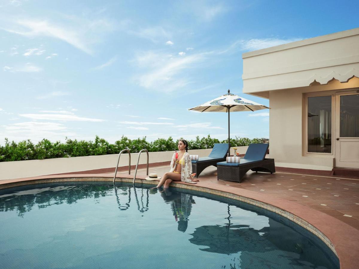 a woman is sitting next to a swimming pool at Taj Krishna in Hyderabad