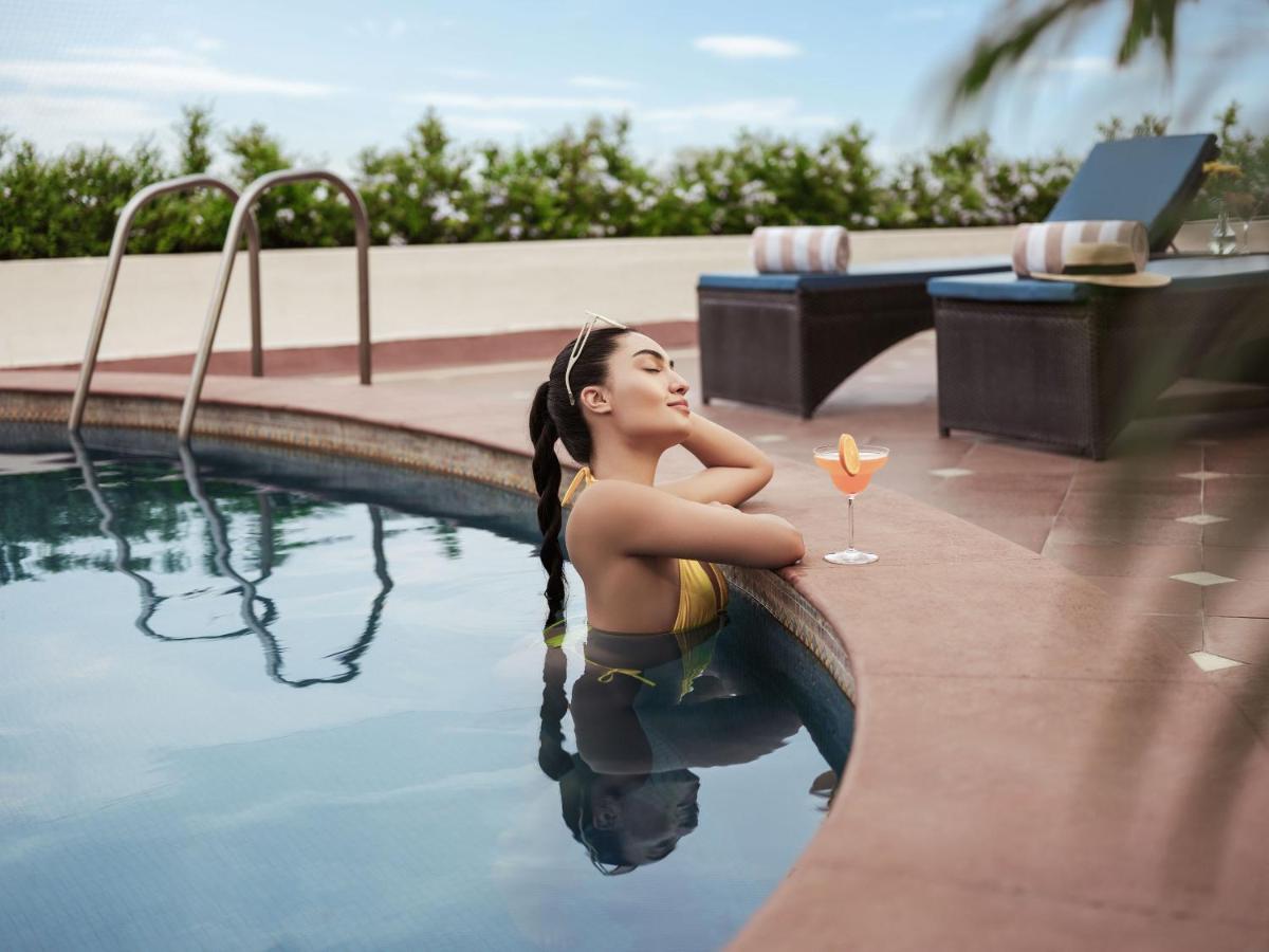 a woman sitting in a swimming pool with a drink at Taj Krishna in Hyderabad