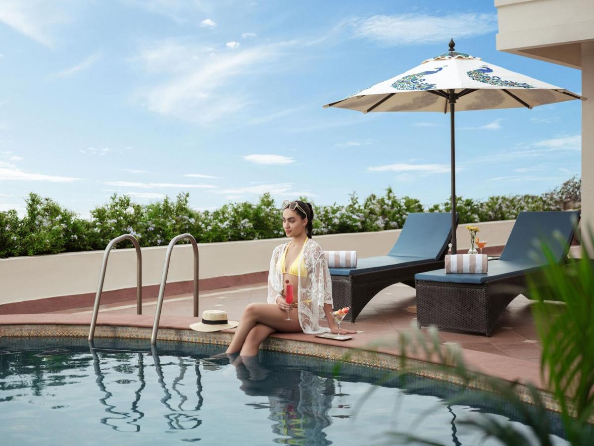 a woman sitting next to a swimming pool at Taj Krishna in Hyderabad