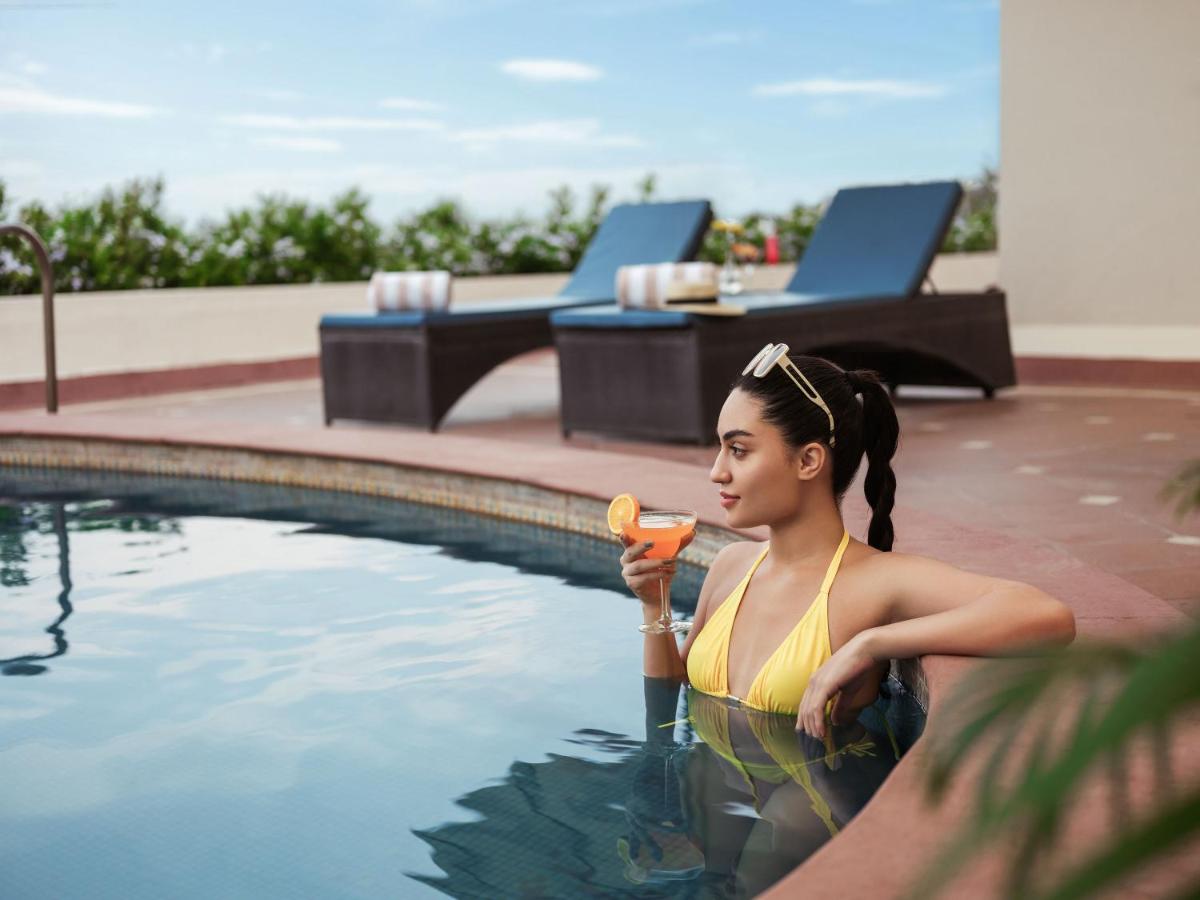 a woman standing in a swimming pool holding a hot dog at Taj Krishna in Hyderabad