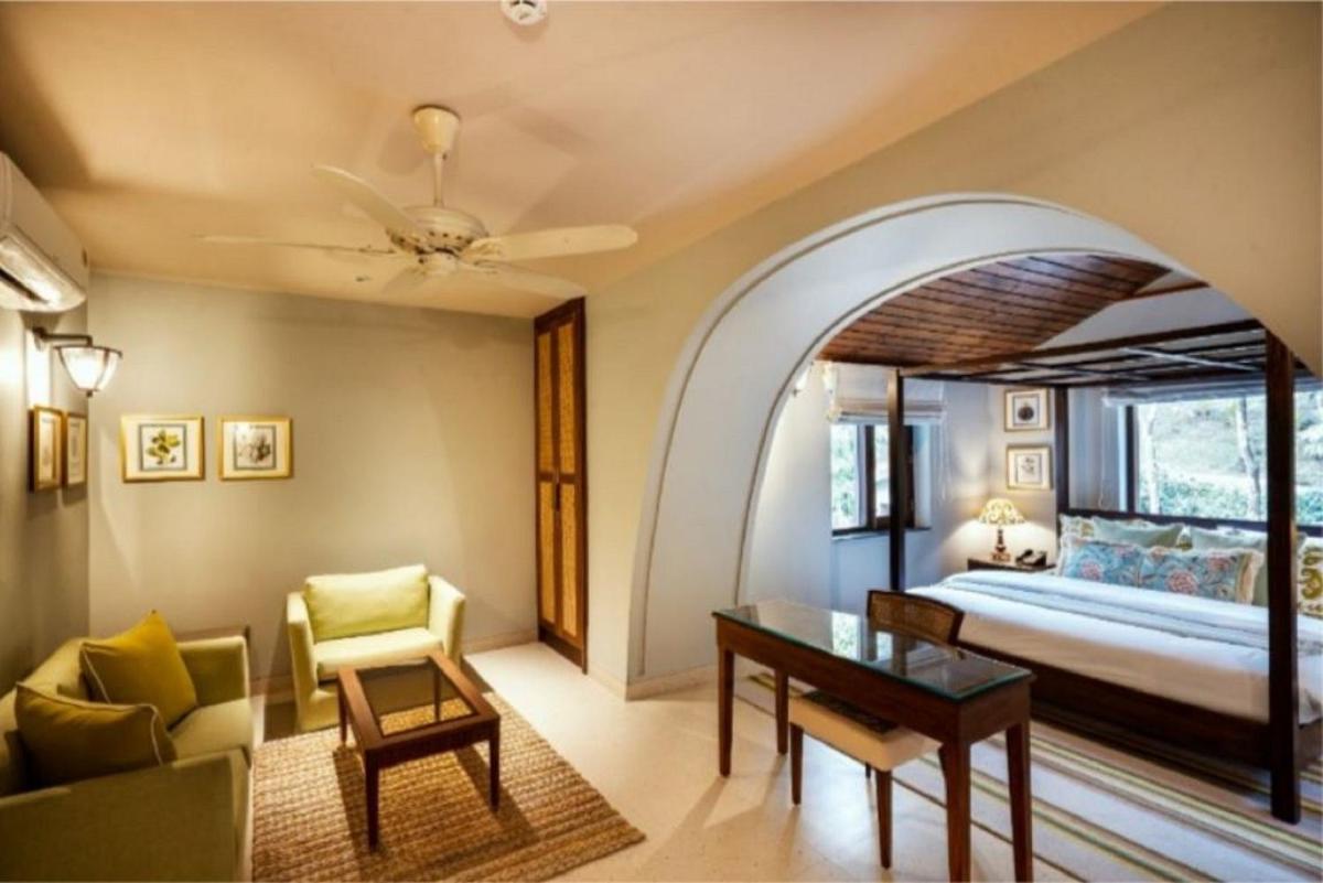 a bedroom with a bed and a living room with a table at Anand Kashi by the Ganges Rishikesh - IHCL Seleqtions in Rishīkesh