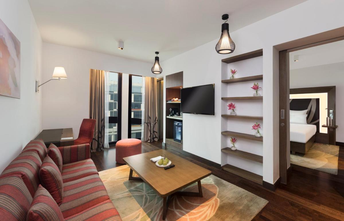 a living room with a couch and a room with a bed at Novotel New Delhi Aerocity in New Delhi