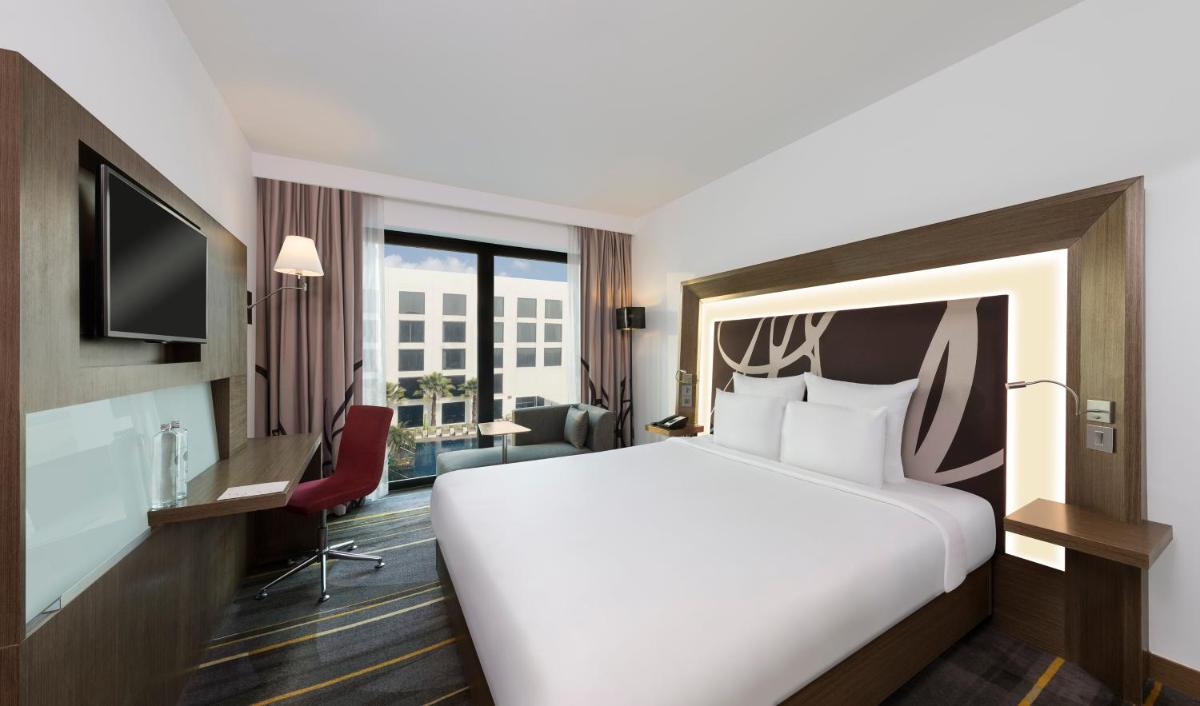 a hotel room with a large white bed and a desk at Novotel New Delhi Aerocity in New Delhi