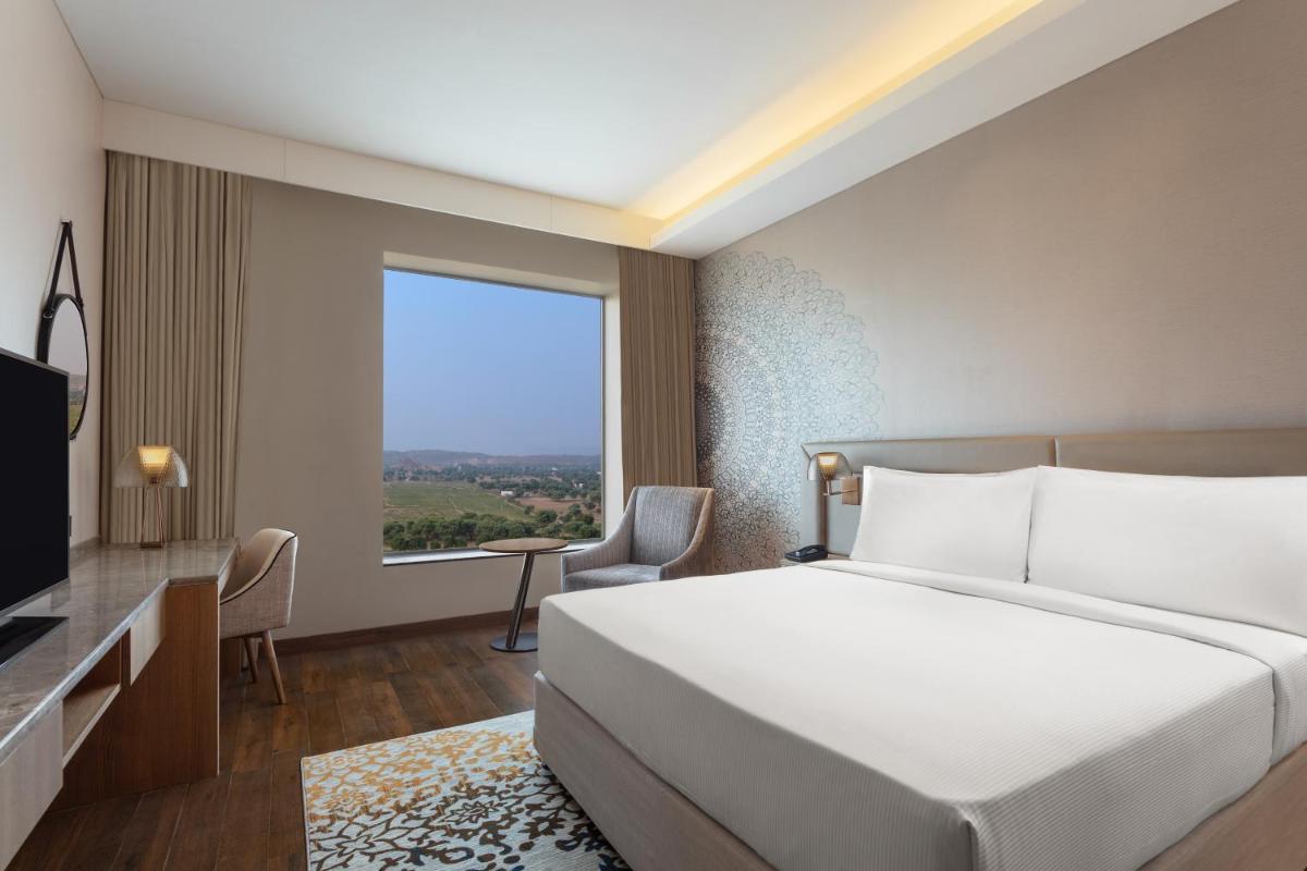 a bedroom with a large bed and a large window at DoubleTree By Hilton Jaipur Amer in Jaipur