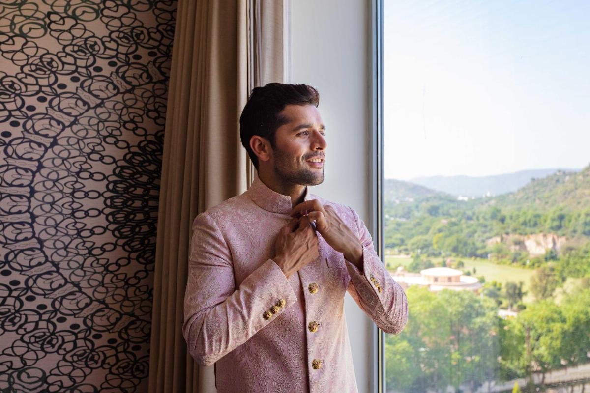 a man is adjusting his tie in front of a window at DoubleTree By Hilton Jaipur Amer in Jaipur