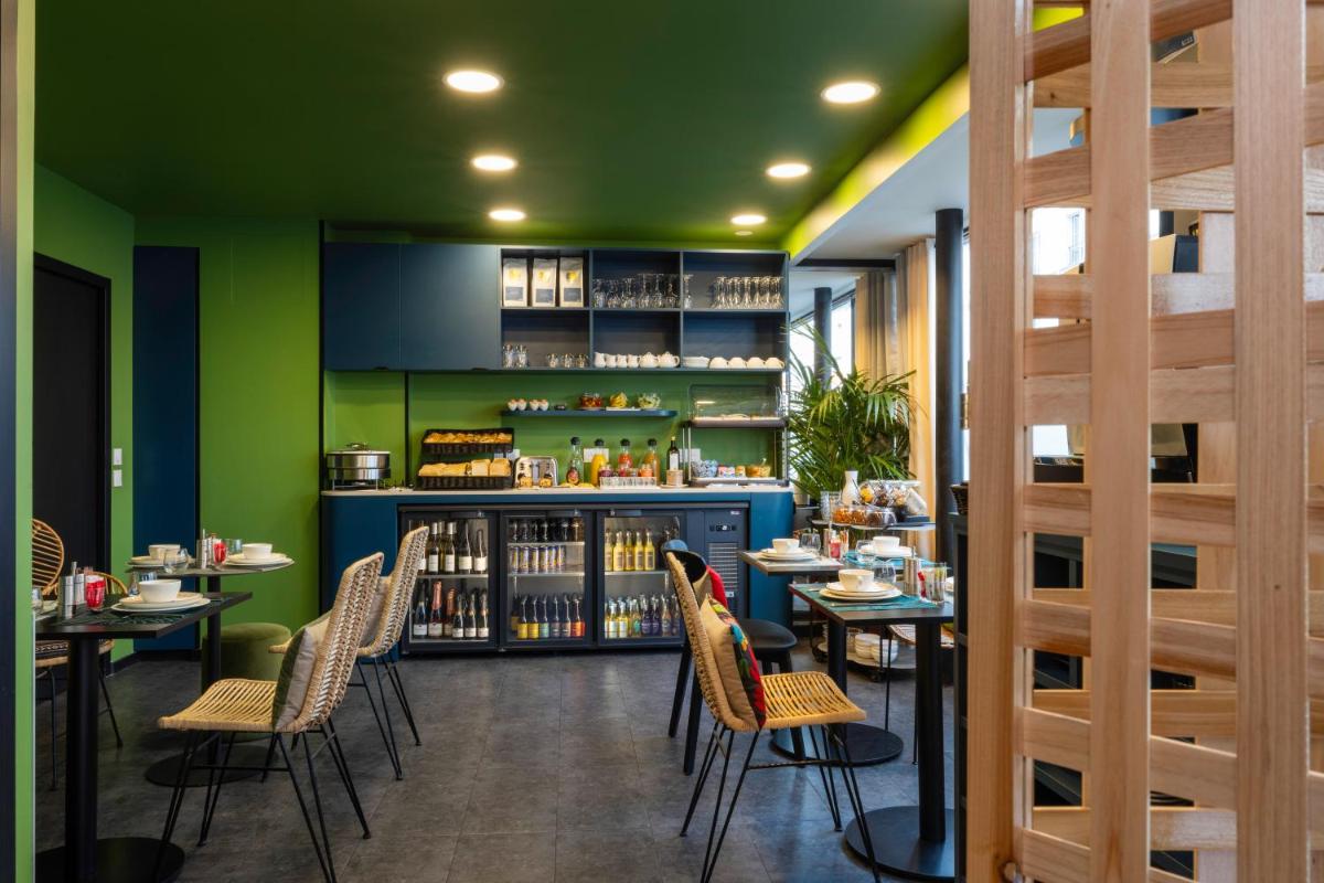un restaurant avec des murs verts, des tables et des chaises dans l'établissement Hotel L’Antoine, à Paris