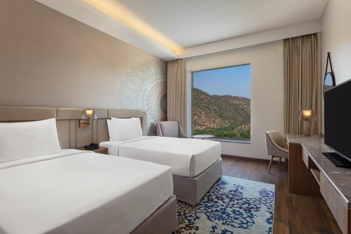 a hotel room with two beds and a large window at DoubleTree By Hilton Jaipur Amer in Jaipur