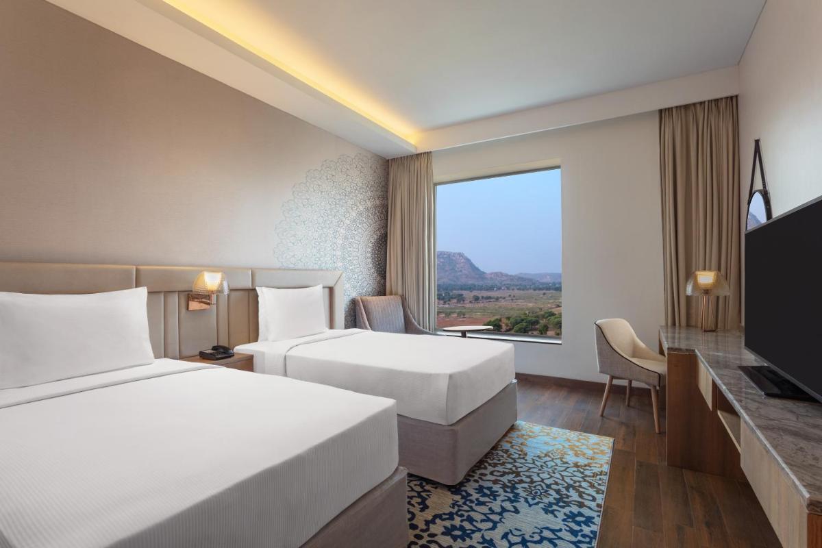 a hotel room with two beds and a large window at DoubleTree By Hilton Jaipur Amer in Jaipur
