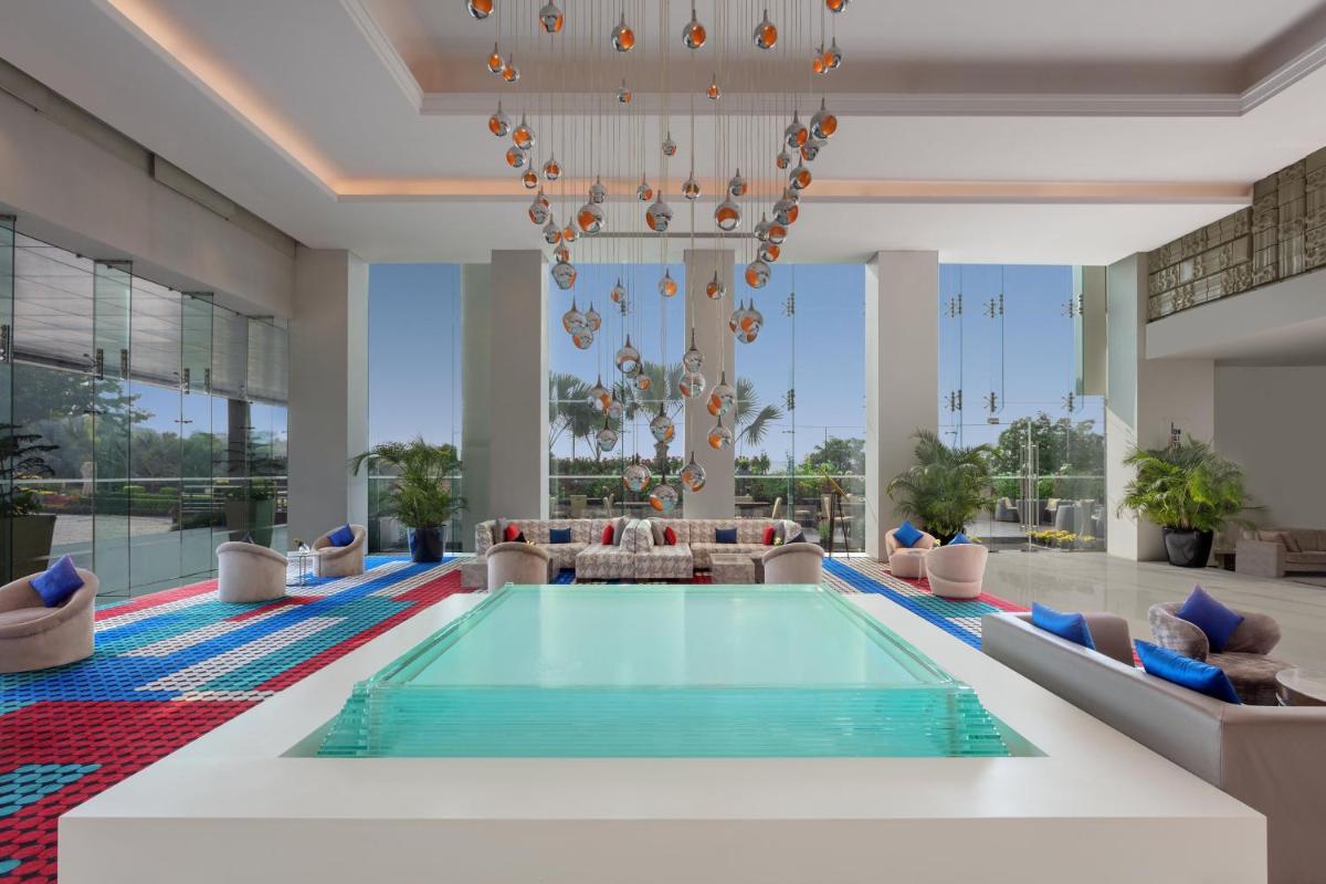 a pool in a hotel lobby with a chandelier at Le Meridien Gurgaon, Delhi NCR in Gurgaon a pool in a hotel lobby with a chandelier at Le Meridien Gurgaon, Delhi NCR in Gurgaon