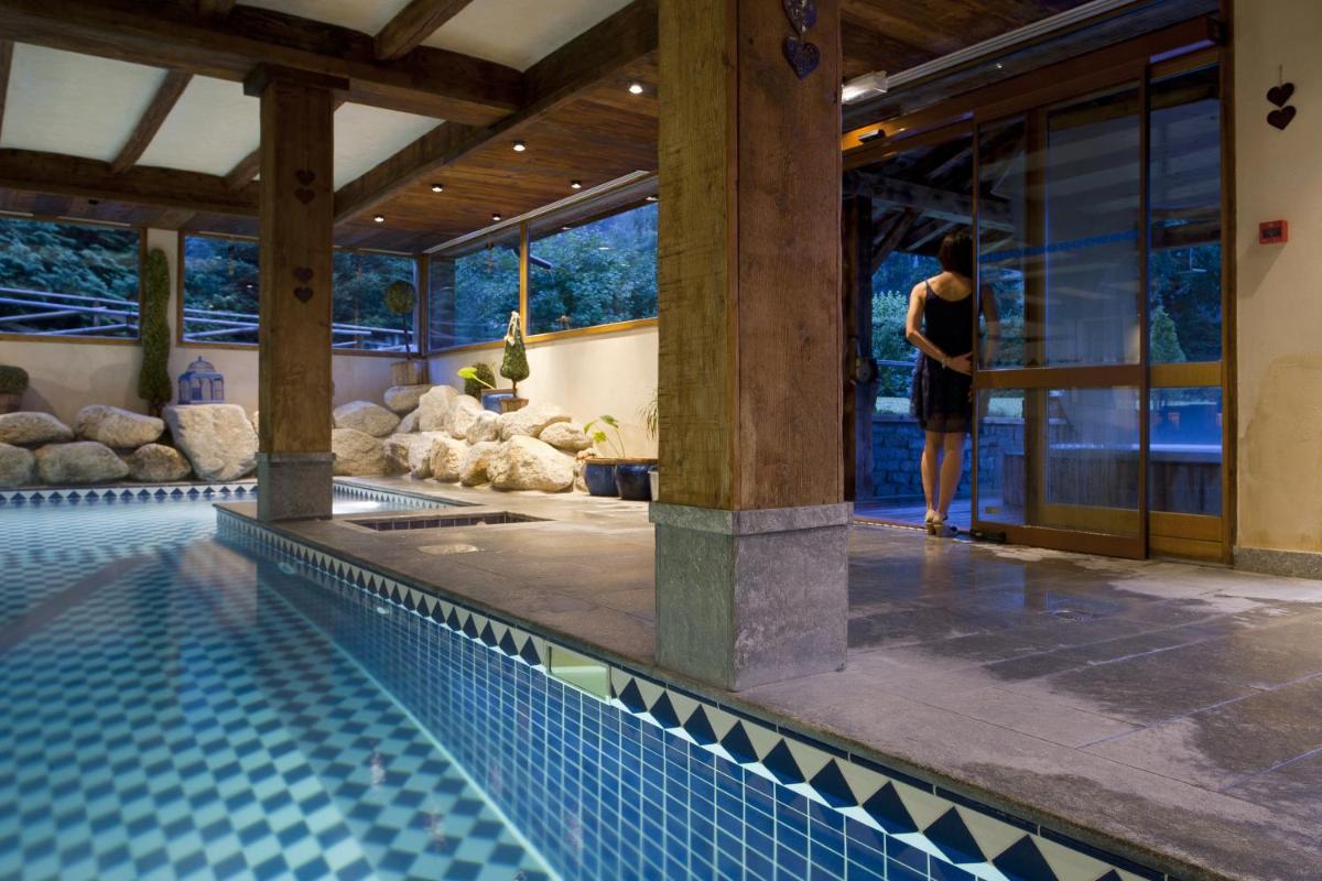 une femme se tient à côté d'une piscine dans l'établissement Les Grands Montets Hotel & Spa, à Chamonix-Mont-Blanc