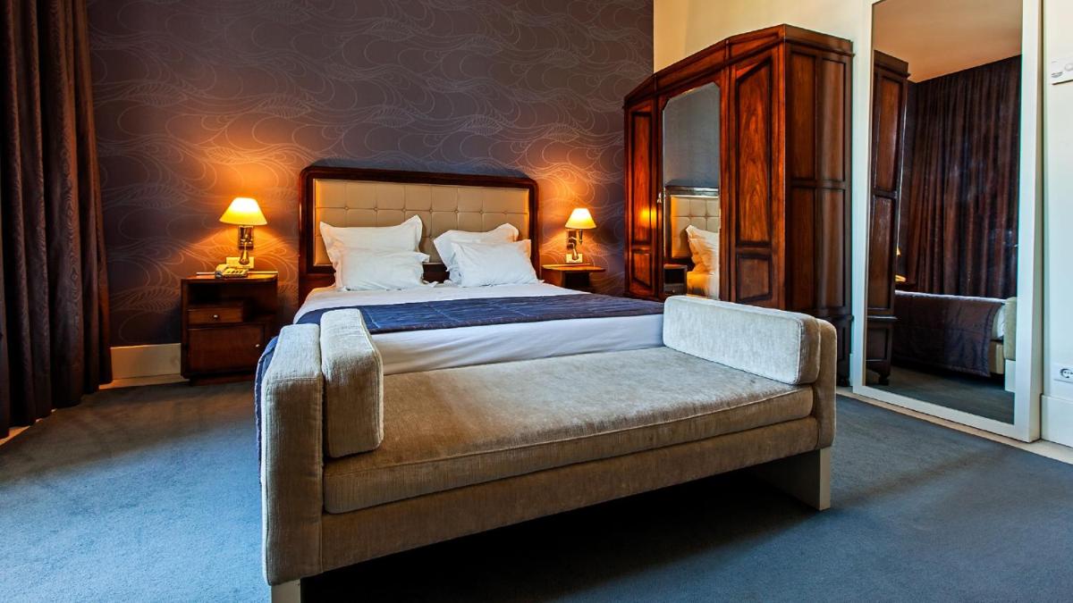 um quarto com uma cama e uma cadeira em Curia Palace Hotel & Spa em Curia