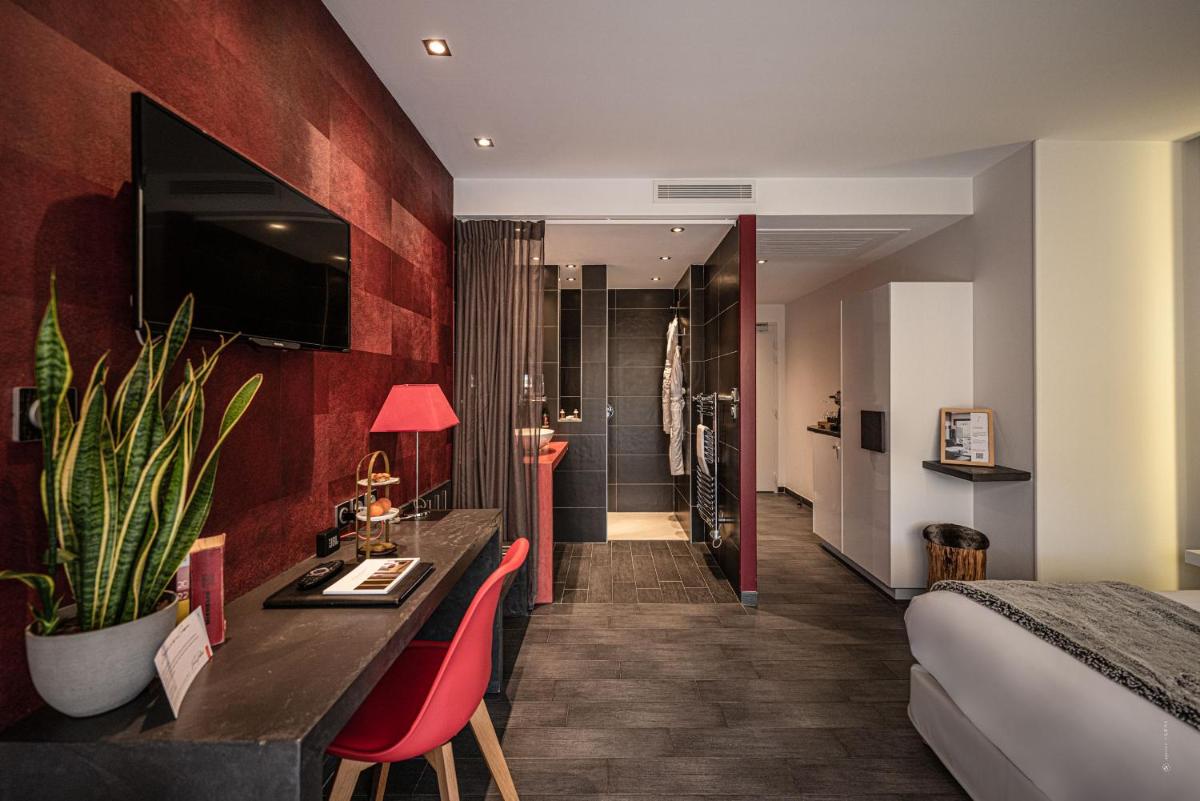 une chambre d'hôtel avec un lit et des murs rouges dans l'établissement Hôtel Le Parc - La Table de Franck Putelat, à Carcassonne