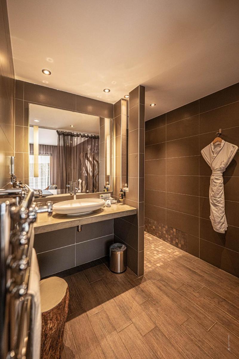 une salle de bain avec un lavabo et un grand miroir dans l'établissement Hôtel Le Parc - La Table de Franck Putelat, à Carcassonne
