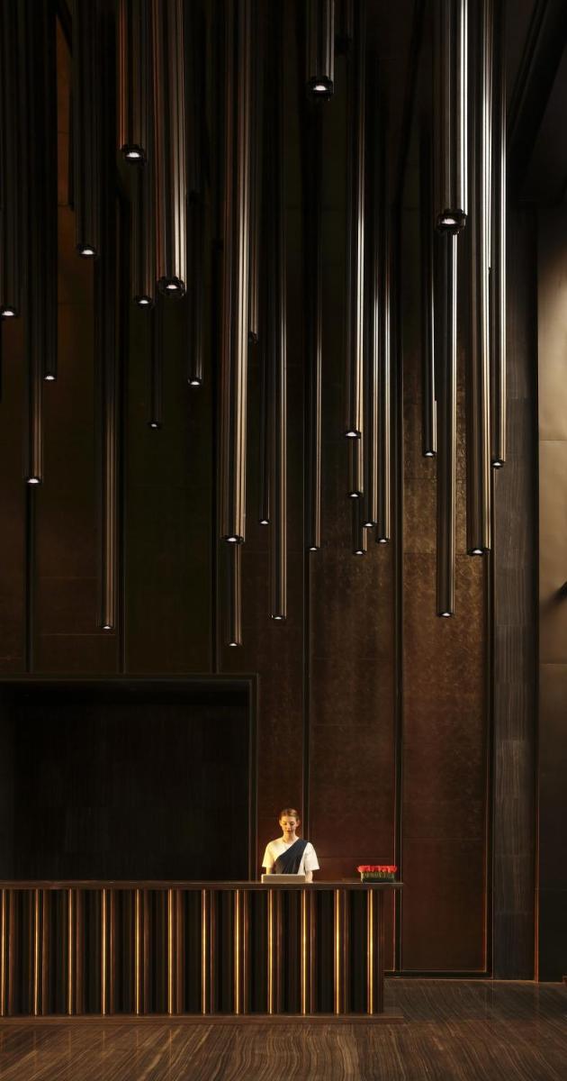 a person sitting on a bench in a room with lights at Roseate House New Delhi in New Delhi a person sitting on a bench in a room with lights at Roseate House New Delhi in New Delhi