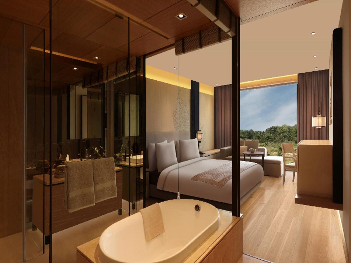 a bedroom with a bed and a bath tub and a sink at Roseate House New Delhi in New Delhi a bedroom with a bed and a bath tub and a sink at Roseate House New Delhi in New Delhi