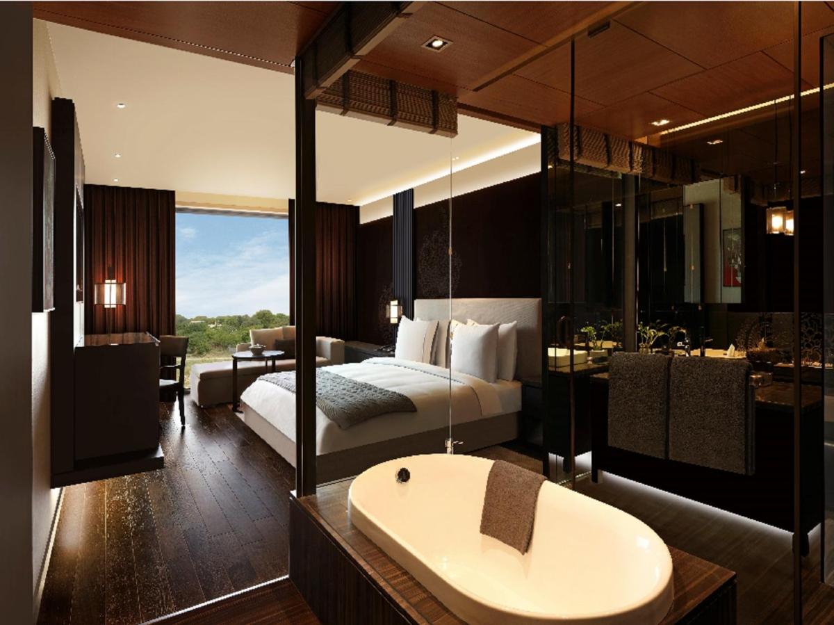 a bedroom with a bed and a bathroom with a sink at Roseate House New Delhi in New Delhi a bedroom with a bed and a bathroom with a sink at Roseate House New Delhi in New Delhi