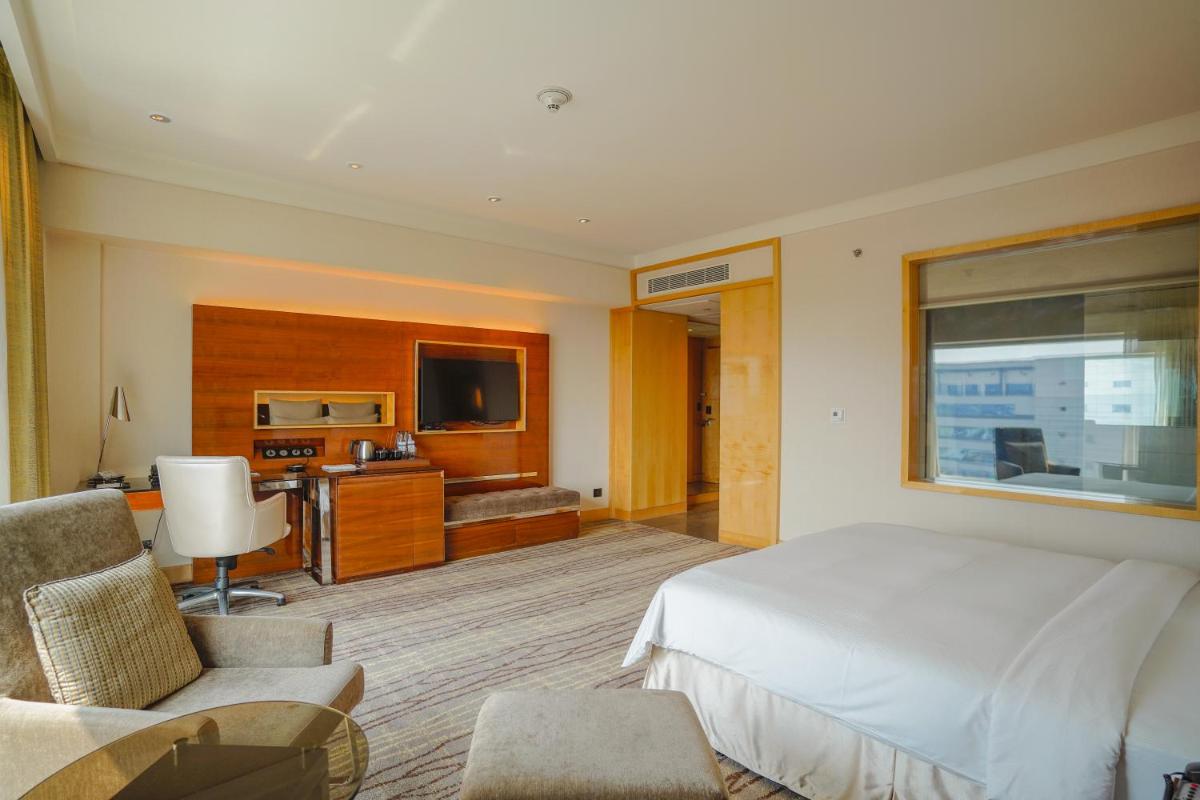 a bedroom with a bed and a desk and a television at Hilton Chennai in Chennai