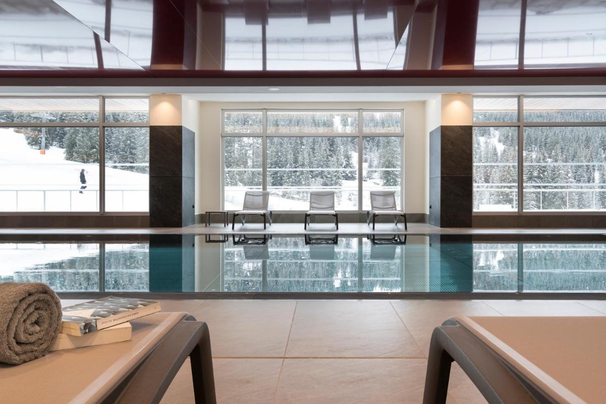une piscine avec des chaises dans un immeuble dans l'établissement MGM Hôtels & Résidences - Hôtel Alhéna, à Flaine