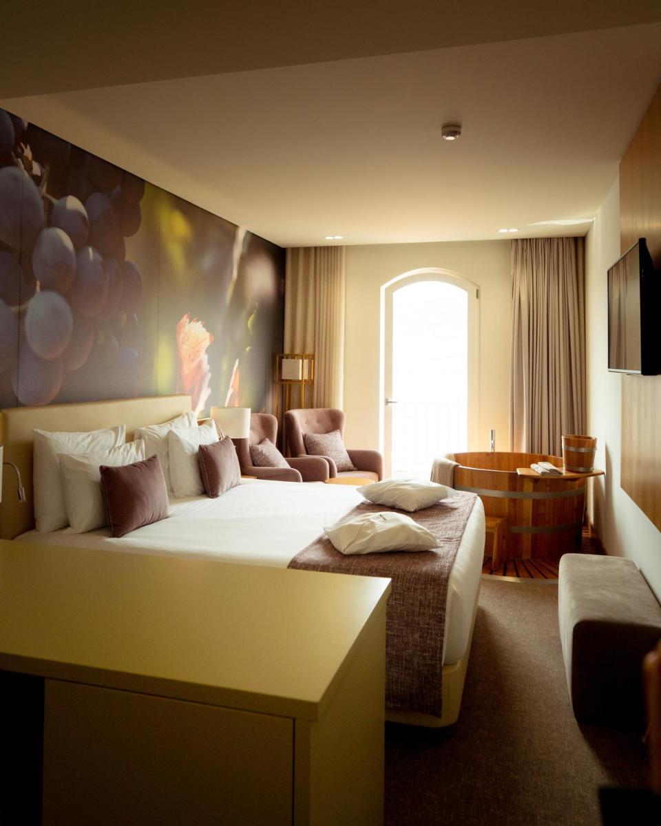 um quarto de hotel com uma cama grande e um sofá em Douro Castelo Signature Hotel & Spa em Lamego mais 44 fotografias