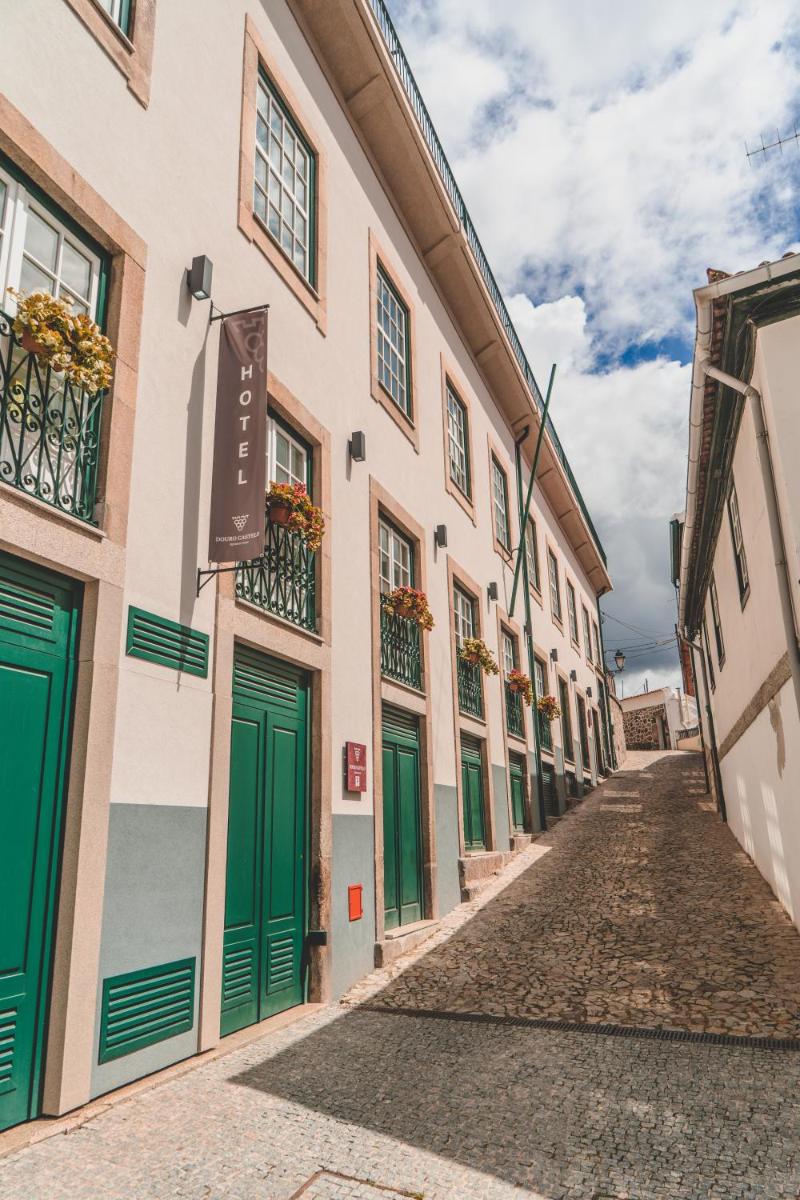 uma rua numa cidade com portas verdes e edifícios em Douro Castelo Signature Hotel & Spa em Lamego
