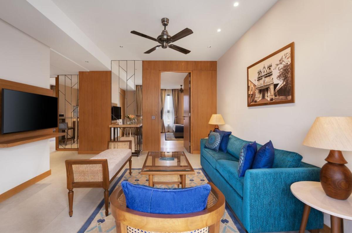 a living room with a blue couch and a tv at The Astor - All Suites Hotel Candolim Goa in Candolim a living room with a blue couch and a tv at The Astor - All Suites Hotel Candolim Goa in Candolim