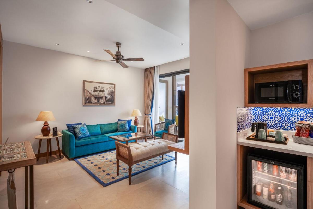 a living room with a blue couch and a fireplace at The Astor - All Suites Hotel Candolim Goa in Candolim a living room with a blue couch and a fireplace at The Astor - All Suites Hotel Candolim Goa in Candolim