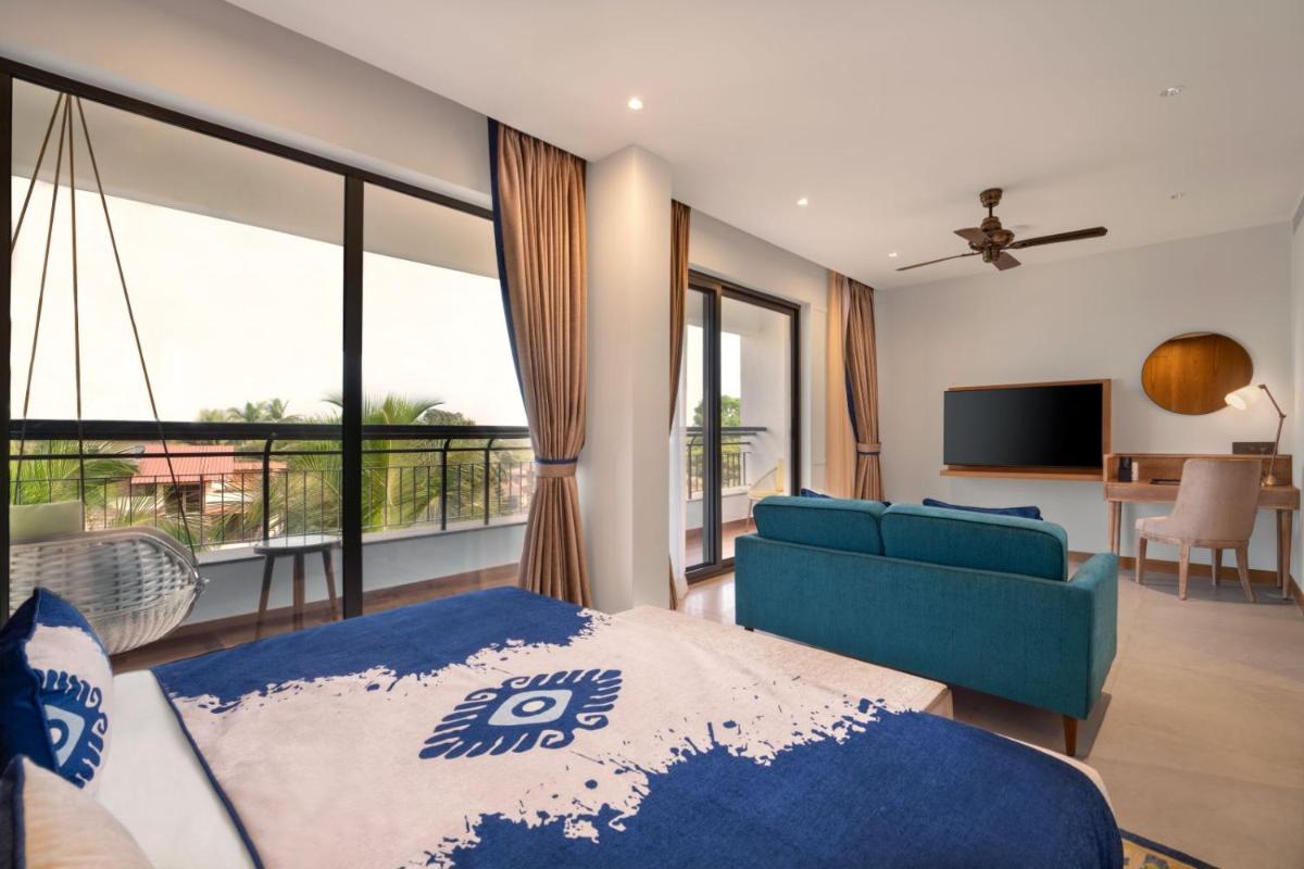 a bedroom with a blue bed and a living room at The Astor - All Suites Hotel Candolim Goa in Candolim a bedroom with a blue bed and a living room at The Astor - All Suites Hotel Candolim Goa in Candolim