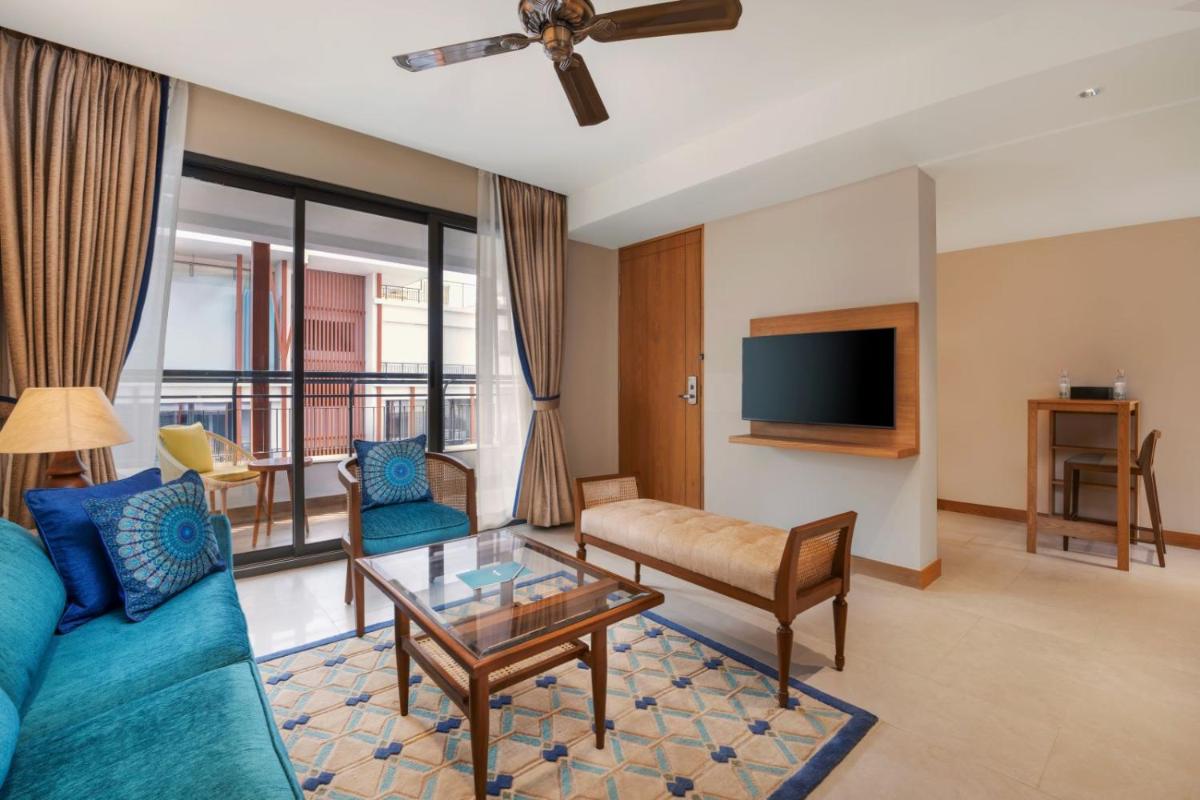 a living room with a blue couch and a tv at The Astor - All Suites Hotel Candolim Goa in Candolim a living room with a blue couch and a tv at The Astor - All Suites Hotel Candolim Goa in Candolim