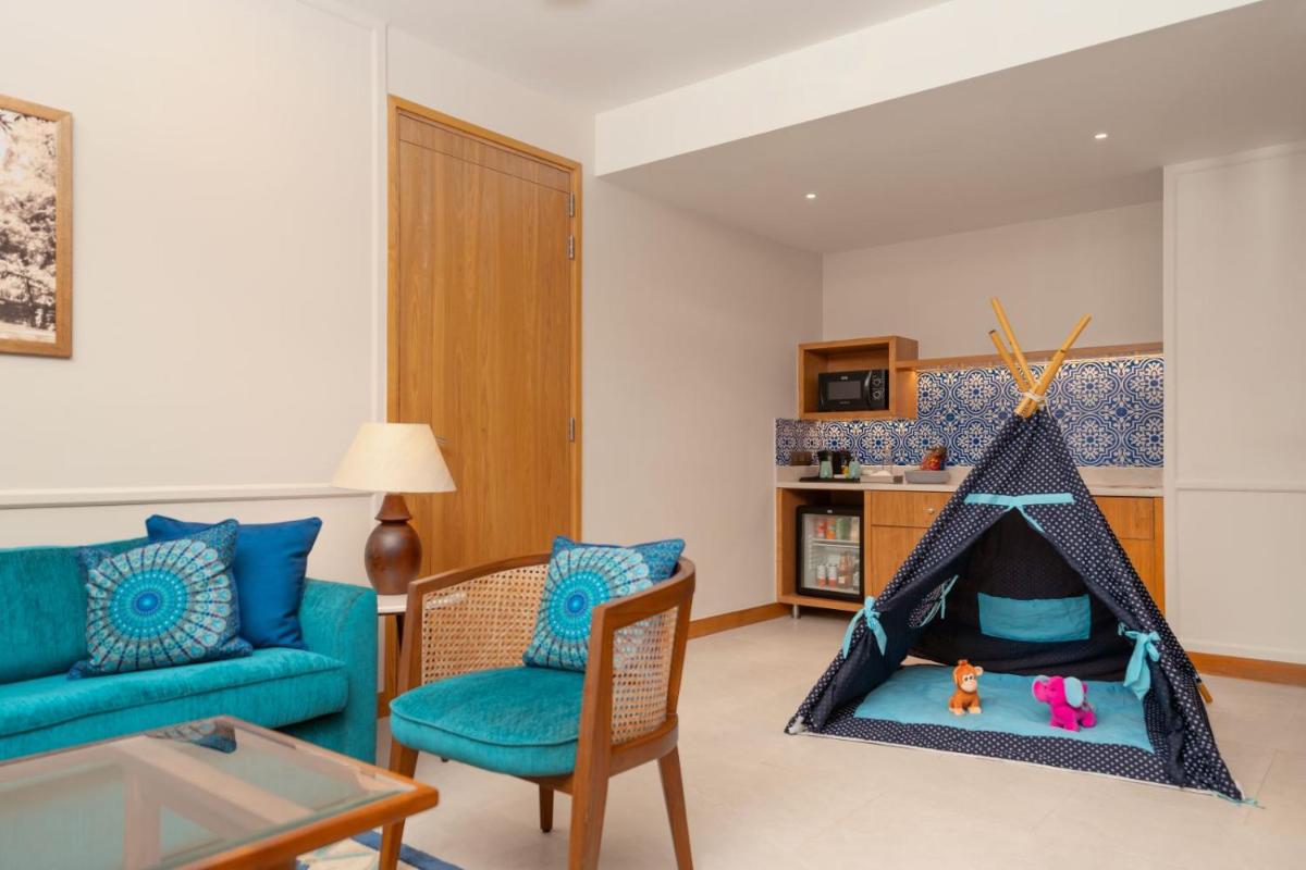 a living room with a blue couch and a play tent at The Astor - All Suites Hotel Candolim Goa in Candolim a living room with a blue couch and a play tent at The Astor - All Suites Hotel Candolim Goa in Candolim