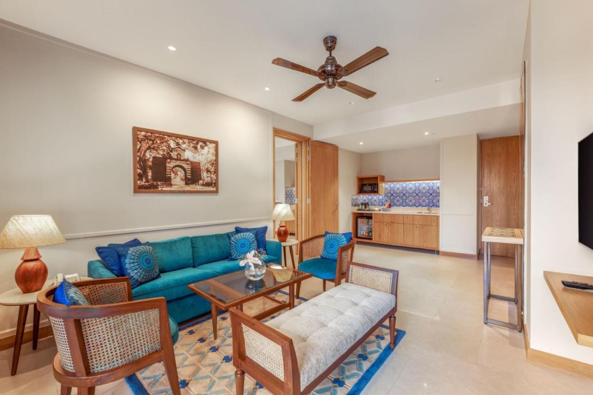 a living room with a blue couch and chairs at The Astor - All Suites Hotel Candolim Goa in Candolim a living room with a blue couch and chairs at The Astor - All Suites Hotel Candolim Goa in Candolim
