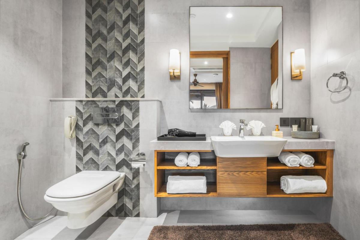 a bathroom with a sink and a toilet and a mirror at The Astor - All Suites Hotel Candolim Goa in Candolim a bathroom with a sink and a toilet and a mirror at The Astor - All Suites Hotel Candolim Goa in Candolim